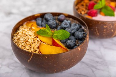 Bir kase granola yoğurt ve dokuma masasında taze böğürtlen. Yoğurt böğürtlen, acai kasesi, spirulina kasesi. Sağlıklı yemek, dengeli kahvaltı. Çilek, yabanmersini, kivi, şeftali, badem ve chia..