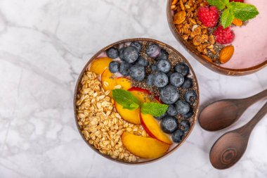 Bir kase granola yoğurt ve dokuma masasında taze böğürtlen. Yoğurt böğürtlen, acai kasesi, spirulina kasesi. Sağlıklı yemek, dengeli kahvaltı. Çilek, yabanmersini, kivi, şeftali, badem ve chia..