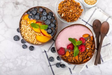 Bir kase granola yoğurt ve dokuma masasında taze böğürtlen. Yoğurt böğürtlen, acai kasesi, spirulina kasesi. Sağlıklı yemek, dengeli kahvaltı. Çilek, yabanmersini, kivi, şeftali, badem ve chia..