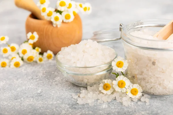 Spa sea salt on texture background. Sea salt with chamomile extract in a glass jar on the table. Beauty concept. Sea bath salt. Place for text, copy space.Close-up.