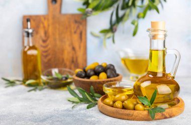 Doku arka planında bir şişe zeytinyağı. Zeytin dallı ve meyveli yağ şişesi. Mesaj için yer. kopyalama alanı. Yemek yağı ve salata sosu..