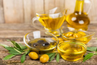 Doku arka planında bir şişe zeytinyağı. Zeytin dallı ve meyveli yağ şişesi. Mesaj için yer. kopyalama alanı. Yemek yağı ve salata sosu..