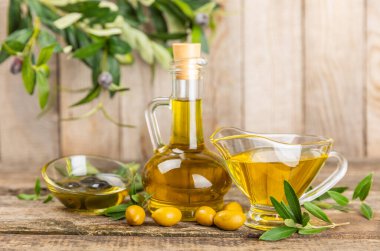 Doku arka planında bir şişe zeytinyağı. Zeytin dallı ve meyveli yağ şişesi. Mesaj için yer. kopyalama alanı. Yemek yağı ve salata sosu..