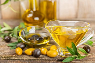 Doku arka planında bir şişe zeytinyağı. Zeytin dallı ve meyveli yağ şişesi. Mesaj için yer. kopyalama alanı. Yemek yağı ve salata sosu..