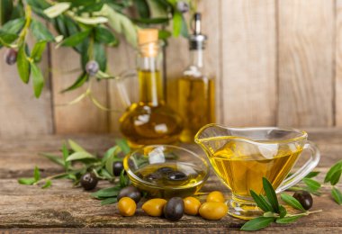 Doku arka planında bir şişe zeytinyağı. Zeytin dallı ve meyveli yağ şişesi. Mesaj için yer. kopyalama alanı. Yemek yağı ve salata sosu..