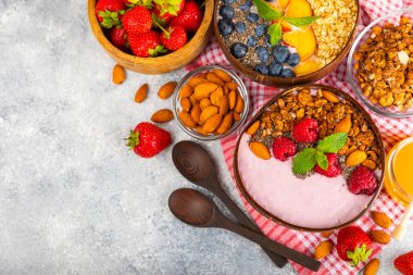 Bir kase granola yoğurt ve dokuma masasında taze böğürtlen. Yoğurt böğürtlen, acai kasesi, spirulina kasesi. Sağlıklı yemek, dengeli kahvaltı. Çilek, yabanmersini, kivi, şeftali, badem ve chia..