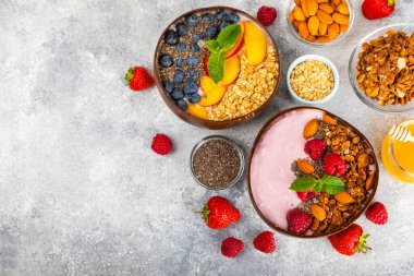 Bir kase granola yoğurt ve dokuma masasında taze böğürtlen. Yoğurt böğürtlen, acai kasesi, spirulina kasesi. Sağlıklı yemek, dengeli kahvaltı. Çilek, yabanmersini, kivi, şeftali, badem ve chia..