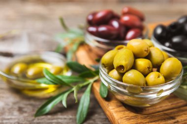 Arka planda yeşil, kırmızı ve siyah zeytin seti. Kâselerde çeşitli zeytin ve taze zeytin yaprakları. Vejetaryen. Zeytin meyveleri. Mesaj için yer. Boşluğu kopyala