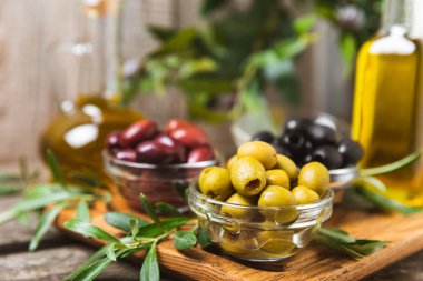 Arka planda yeşil, kırmızı ve siyah zeytin seti. Kâselerde çeşitli zeytin ve taze zeytin yaprakları. Vejetaryen. Zeytin meyveleri. Mesaj için yer. Boşluğu kopyala