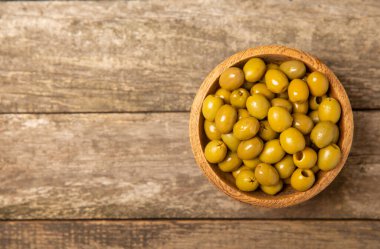 Arka planda yeşil zeytin. Kâselerde çeşitli zeytin ve taze zeytin yaprakları. Vejetaryen. Zeytin meyveleri. Mesaj için yer. Boşluğu kopyala.