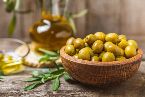 Green olives on  background. Various types of olives in bowls and fresh olive leaves. Vegan. Olive fruits. Place for text. Copy space.