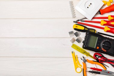 Arka planda elektrikli aletler var. Çoklu metre, inşaat bandı, elektrik bandı, tornavida, pense, otomatik yalıtım striptizcisi, soket ve LED lamba. Düz çizgi. elektrikçi kavramı.