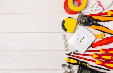 Arka planda elektrikli aletler var. Çoklu metre, inşaat bandı, elektrik bandı, tornavida, pense, otomatik yalıtım striptizcisi, soket ve LED lamba. Düz çizgi. elektrikçi kavramı.