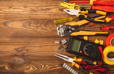 Arka planda elektrikli aletler var. Çoklu metre, inşaat bandı, elektrik bandı, tornavida, pense, otomatik yalıtım striptizcisi, soket ve LED lamba. Düz çizgi. elektrikçi kavramı.