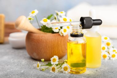 Eski ahşap arka planda papatya yağı bulunan cam şişe. Papatya çiçekleri, yaklaşın. Aromaterapi, spa ve bitkisel ilaç malzemeleri. Güzellik konsepti. Uzayı kopyala. Doğal Kozmetik