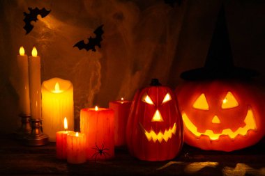 Cadılar Bayramı balkabağı feneri, koyu dokulu arka planda mumlar, örümcek ağları ve örümcekler. Cadılar Bayramı balkabağı Jack Lantern. Bayram kavramı. Cadılar Bayramı Jack o Lantern Balkabağı, ürkütücü yüzlü.