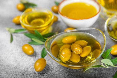 Doku arka planında bir şişe zeytinyağı. Yağ şişesi ve dallı bir kase ve zeytin meyvesi. Mesaj için yer. kopyalama alanı. Yemek yağı ve salata sosu..