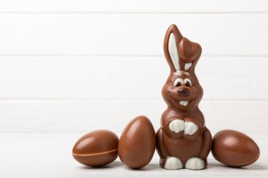 Açık dokuma masasında paskalya çikolatası tavşanı. Çikolatalı yumurta ve diğer tatlılar. Paskalya kutlaması. Paskalya tatlıları masada. Mesaj için yer. Boşluğu kopyala.