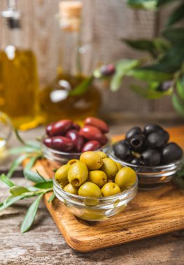 Arka planda yeşil, kırmızı ve siyah zeytin seti. Kâselerde çeşitli zeytin ve taze zeytin yaprakları. Vejetaryen. Zeytin meyveleri. Mesaj için yer. Boşluğu kopyala.