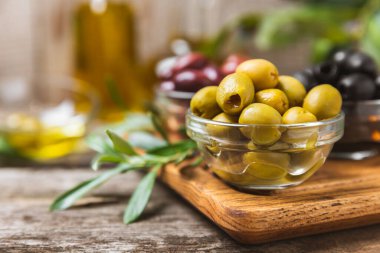 Arka planda yeşil, kırmızı ve siyah zeytin seti. Kâselerde çeşitli zeytin ve taze zeytin yaprakları. Vejetaryen. Zeytin meyveleri. Mesaj için yer. Boşluğu kopyala.