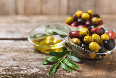 Arka planda yeşil, kırmızı ve siyah zeytin seti. Kâselerde çeşitli zeytin ve taze zeytin yaprakları. Vejetaryen. Zeytin meyveleri. Mesaj için yer. Boşluğu kopyala.