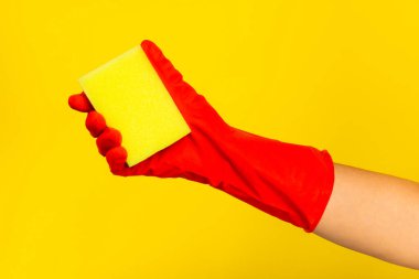 Kırmızı lastik eldiven ve sarı süngerle temizlenmiş. Sarı temizleme süngeri mesaj için kullanılıyor. Temizlik konsepti. Bulaşıklar için sünger.