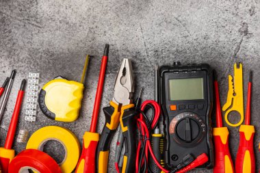 Mermer zemin üzerinde mermer arkaplan üzerinde elektrikli ekipman. Üst görünüm. Elektrik aracı seti. Çoklu metre, test cihazı, tornavida, kesiciler, koli bandı, lamba, mezura, mezura ve kablo..