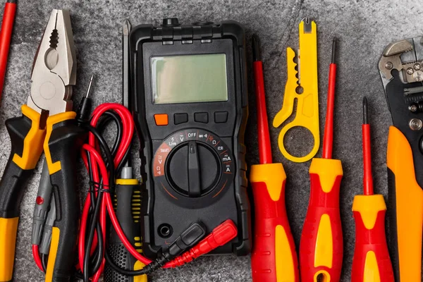 Mermer zemin üzerinde mermer arkaplan üzerinde elektrikli ekipman. Üst görünüm. Elektrik aracı seti. Çoklu metre, test cihazı, tornavida, kesiciler, koli bandı, lamba, mezura, mezura ve kablo..