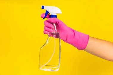 Sarı arka planda temizlik ürünleri tutan lastik eldivenli bir el. Pankart. Temizlik kavramı.