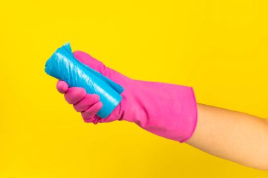 Renkli bir arka planda çöp torbası tutan bir kadının elleri. Arka plandaki çöpler için plastik poşetlerle sarın. Mesaj için yer. Çöp ayıklama.