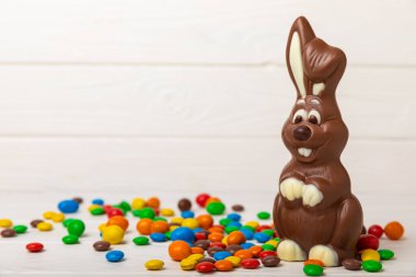 Açık dokuma masasında paskalya çikolatası tavşanı. Çikolatalı yumurta ve diğer tatlılar. Paskalya kutlaması. Paskalya tatlıları masada. Mesaj için yer. Boşluğu kopyala.