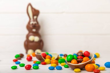 Açık dokuma masasında paskalya çikolatası tavşanı. Çikolatalı yumurta ve diğer tatlılar. Paskalya kutlaması. Paskalya tatlıları masada. Mesaj için yer. Boşluğu kopyala.