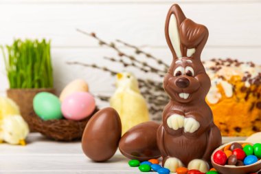 Açık dokuma masasında paskalya çikolatası tavşanı. Çikolatalı yumurta ve diğer tatlılar. Paskalya kutlaması. Paskalya tatlıları masada. Mesaj için yer. Boşluğu kopyala.