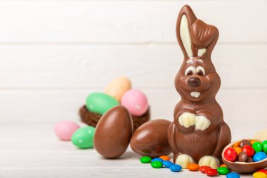 Açık dokuma masasında paskalya çikolatası tavşanı. Çikolatalı yumurta ve diğer tatlılar. Paskalya kutlaması. Paskalya tatlıları masada. Mesaj için yer. Boşluğu kopyala.