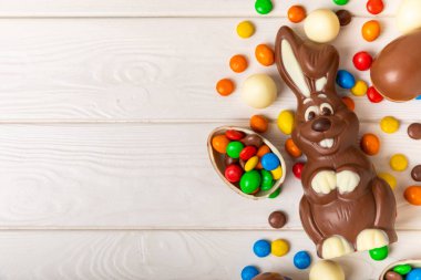 Açık dokuma masasında paskalya çikolatası tavşanı. Çikolatalı yumurta ve diğer tatlılar. Paskalya kutlaması. Paskalya tatlıları masada. Mesaj için yer. Boşluğu kopyala.