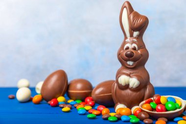 Açık dokuma masasında paskalya çikolatası tavşanı. Çikolatalı yumurta ve diğer tatlılar. Paskalya kutlaması. Paskalya tatlıları masada. Mesaj için yer. Boşluğu kopyala.