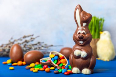 Açık dokuma masasında paskalya çikolatası tavşanı. Çikolatalı yumurta ve diğer tatlılar. Paskalya kutlaması. Paskalya tatlıları masada. Mesaj için yer. Boşluğu kopyala.