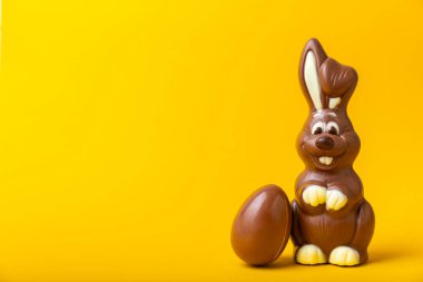 Açık dokuma masasında paskalya çikolatası tavşanı. Çikolatalı yumurta ve diğer tatlılar. Paskalya kutlaması. Paskalya tatlıları masada. Mesaj için yer. Boşluğu kopyala.