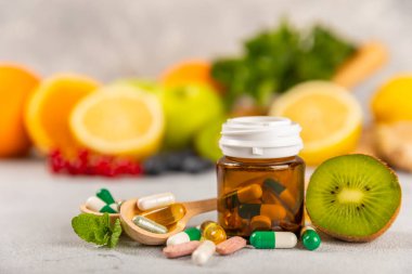 Vitaminler ve takviyeler. Arka planda bulunan bir kavanozdaki vitamin haplarının çeşitliliği. Taze ve sağlıklı meyveli multivitaminler. Yiyecek takviyeleri. Düz yatıyordu. Metin için boşluk. Boşluğu kopyala