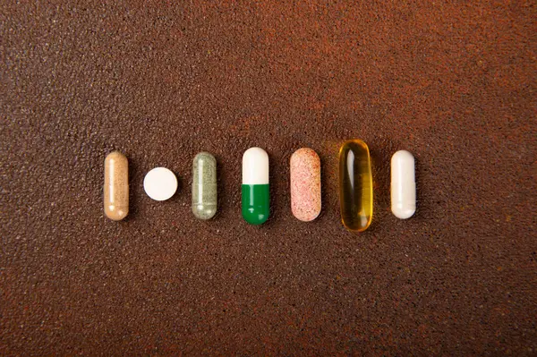 Vitamins and supplements. Variety of vitamin tablets on a brown background. Multivitamins for every day. Nutritional supplements. Flat lay. Space for text.Copy space