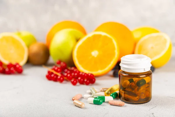 Vitamins and supplements. Variety of vitamin tablets in a jar on a texture background.Multivitamins with fresh and healthy fruits.Food supplements. Flat lay. Space for text.Copy space