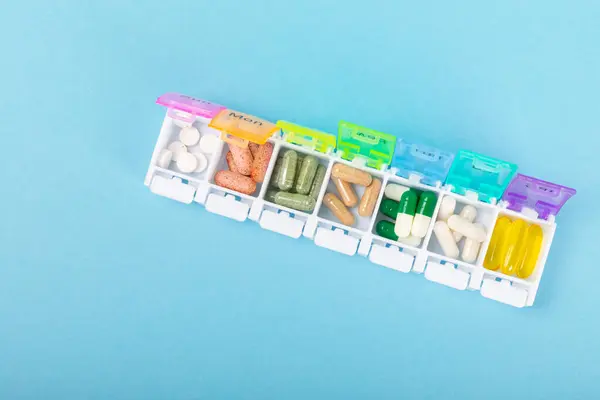 Vitamins and supplements. Variety of vitamin tablets in a pillbox on a blue background. Multivitamins for every day. Nutritional supplements. Flat lay. Space for text.Copy space