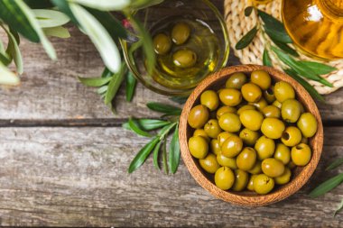 Beyaz ahşap arka planda yeşil zeytin. Taze zeytin yapraklı zeytin yağı ve kâse içinde çeşitli zeytin türleri. Uzayı kopyala Mesaj için yer. Akdeniz yemekleri. Vejetaryen.