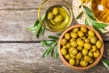 Beyaz ahşap arka planda yeşil zeytin. Taze zeytin yapraklı zeytin yağı ve kâse içinde çeşitli zeytin türleri. Uzayı kopyala Mesaj için yer. Akdeniz yemekleri. Vejetaryen.