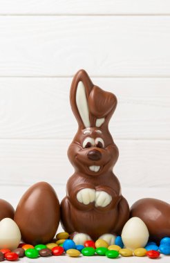 Açık dokuma masasında paskalya çikolatası tavşanı. Çikolatalı yumurta ve diğer tatlılar. Paskalya kutlaması. Paskalya tatlıları masada. Mesaj için yer. Boşluğu kopyala.