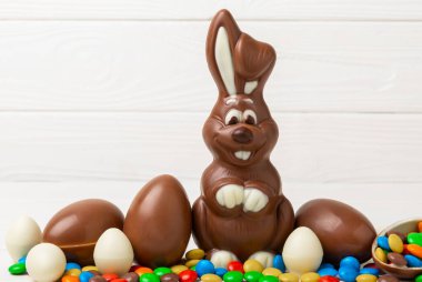 Açık dokuma masasında paskalya çikolatası tavşanı. Çikolatalı yumurta ve diğer tatlılar. Paskalya kutlaması. Paskalya tatlıları masada. Mesaj için yer. Boşluğu kopyala.
