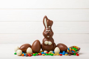 Açık dokuma masasında paskalya çikolatası tavşanı. Çikolatalı yumurta ve diğer tatlılar. Paskalya kutlaması. Paskalya tatlıları masada. Mesaj için yer. Boşluğu kopyala.