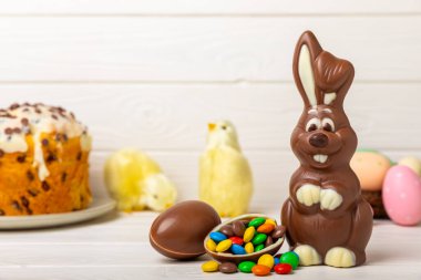 Açık dokuma masasında paskalya çikolatası tavşanı. Çikolatalı yumurta ve diğer tatlılar. Paskalya kutlaması. Paskalya tatlıları masada. Mesaj için yer. Boşluğu kopyala.