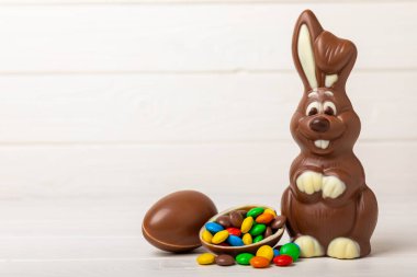 Açık dokuma masasında paskalya çikolatası tavşanı. Çikolatalı yumurta ve diğer tatlılar. Paskalya kutlaması. Paskalya tatlıları masada. Mesaj için yer. Boşluğu kopyala.