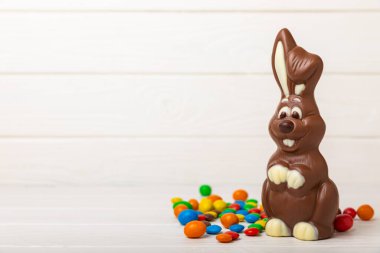 Açık dokuma masasında paskalya çikolatası tavşanı. Çikolatalı yumurta ve diğer tatlılar. Paskalya kutlaması. Paskalya tatlıları masada. Mesaj için yer. Boşluğu kopyala.